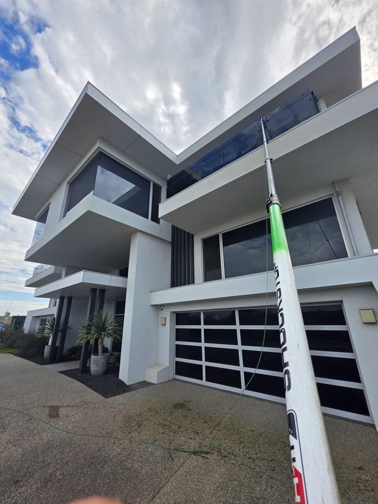 Water-fed pole cleaning the upper windows of a newly built two-storey home