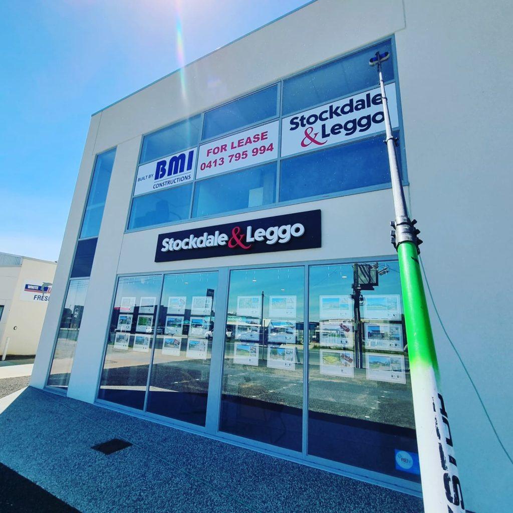 Excel Window Cleaning cleaning the glass shopfront of a real estate office